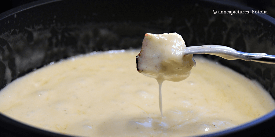 Eine Gabel hat ein Stück Brot aufgepiekst und tunkt in das cremig aussehende Kürbis-Fondue
