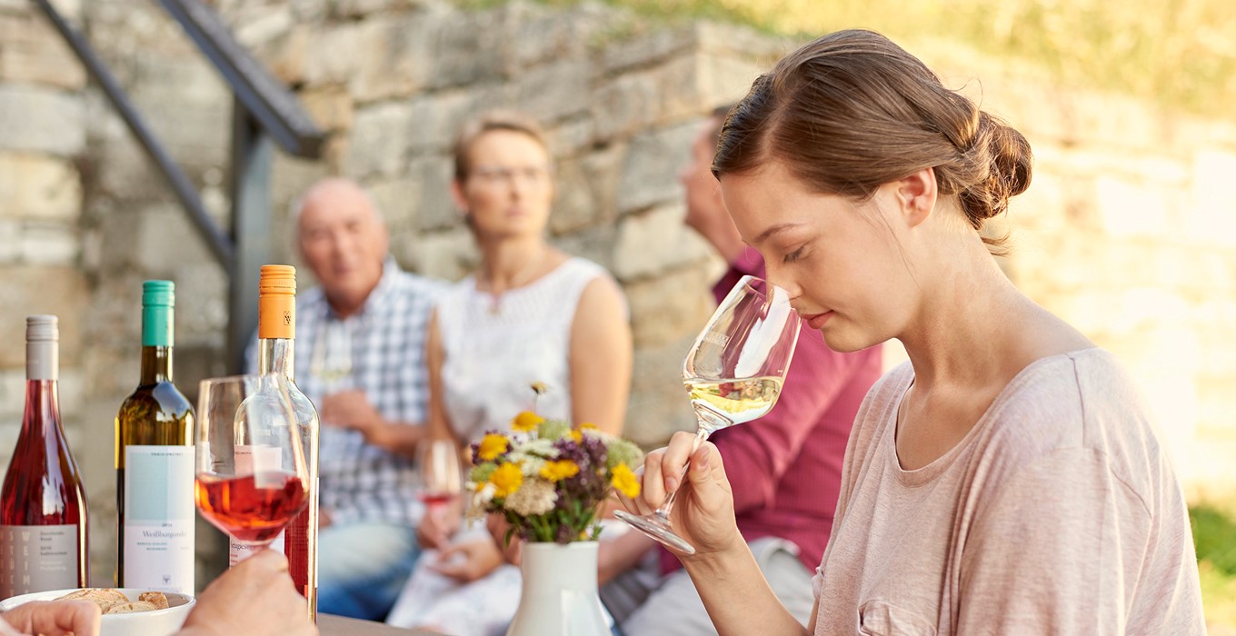 Eine Frau riecht prüfend in ihr Weinglas hinein
