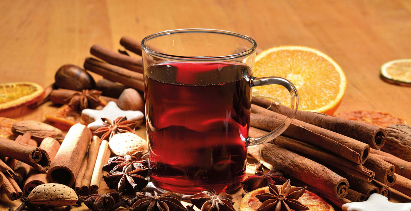 Ein Glas Glühwein umringt von weihnachtlichen Gewürzen